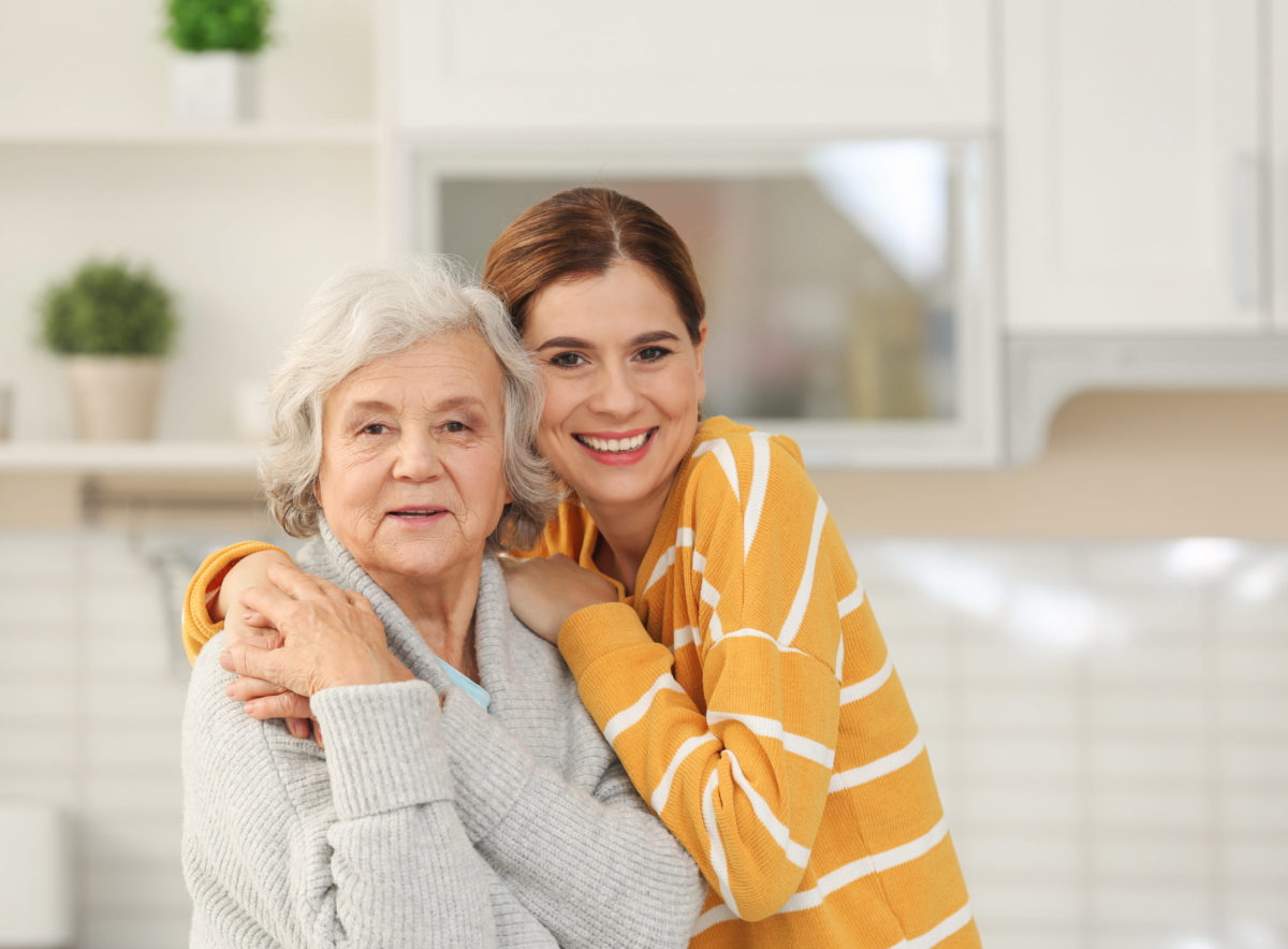 Elderly woman with female caregiver in kitchen.